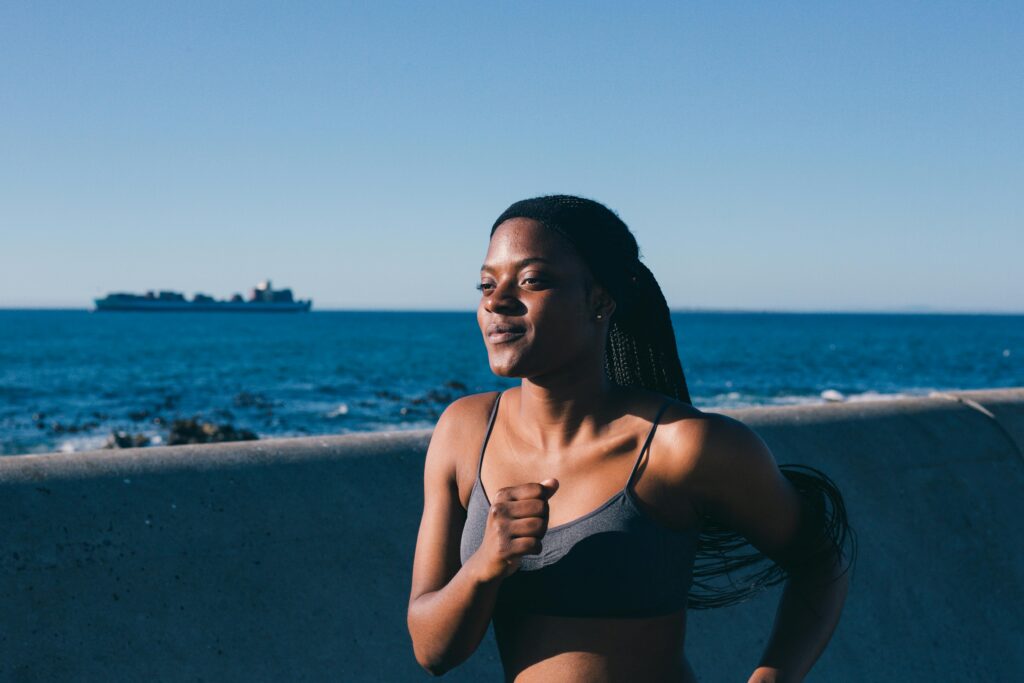 A woman jogging along the seaside, embodying a healthy lifestyle and enjoying an outdoor workout.