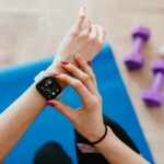 A woman checks fitness data on her smartwatch during a workout at home.